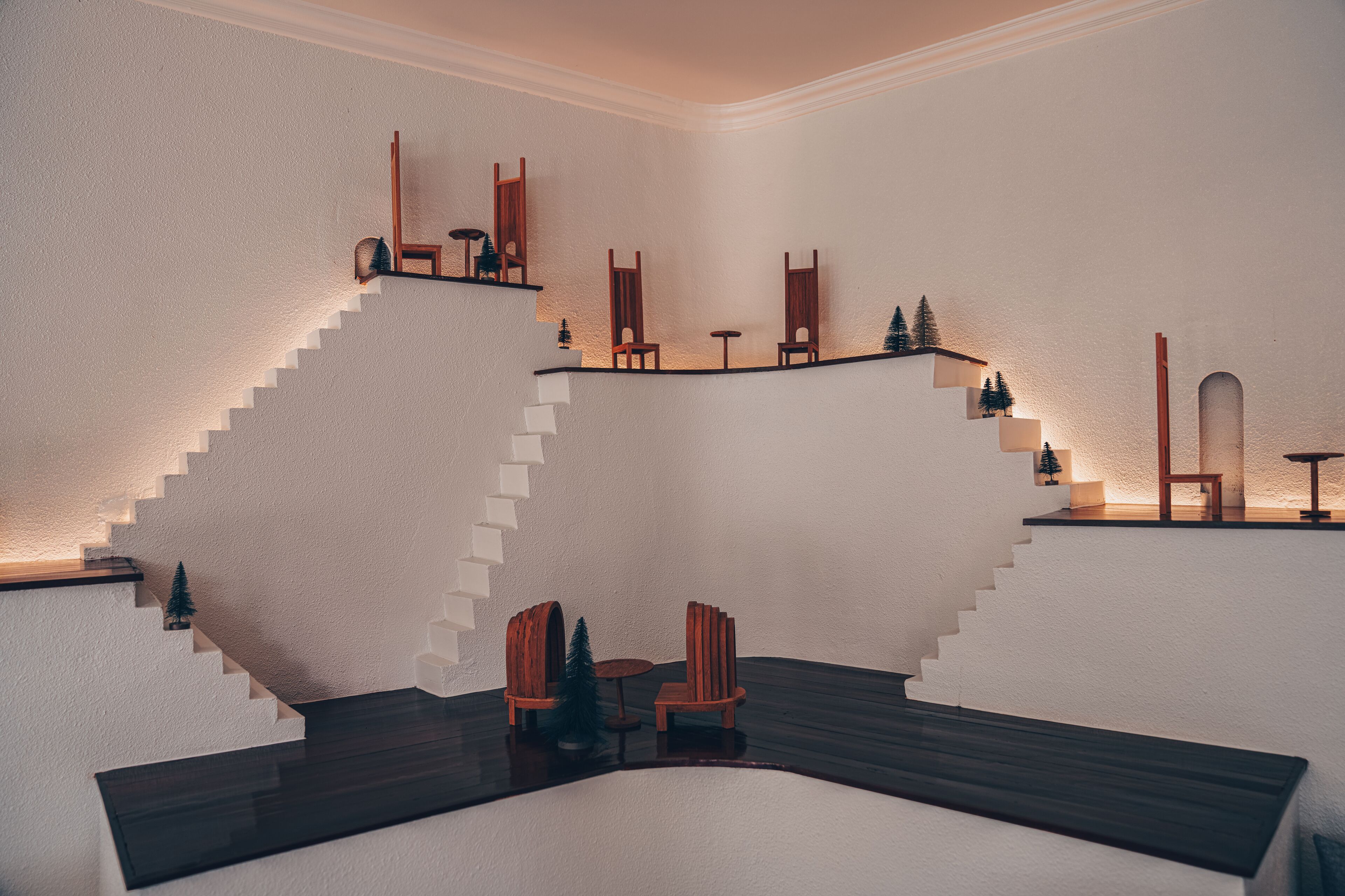 A modern interior with a unique staircase design, wooden furniture, and small decorative trees.
