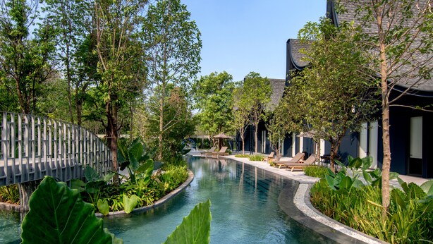 A pool area with lounge chairs, surrounded by greenery and modern architecture. - Hotel Labaris Khao Yai (Pak Chong)