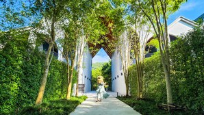 A pathway leading to a building with a white facade and arched entrance, surrounded by lush greenery. - Hotel Labaris Khao Yai (Pak Chong)