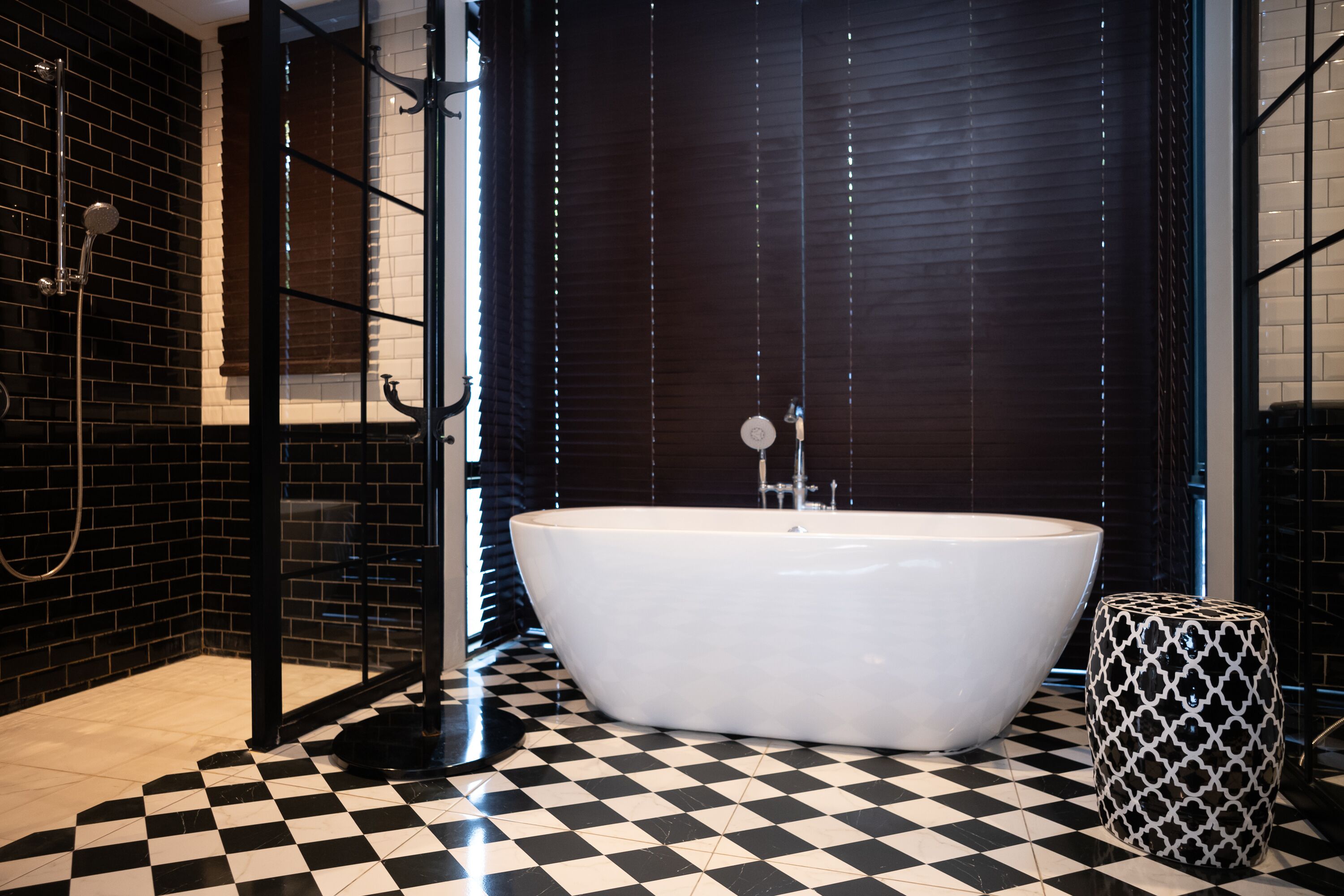 A bathroom with a checkered floor, a freestanding bathtub, and a glass shower enclosure.