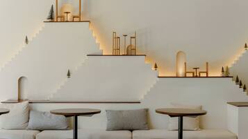 A modern interior with a sofa and round tables, a staircase with geometric wall art, and a minimalist design.