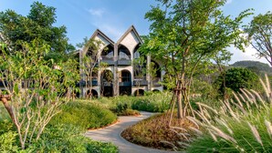 A building with a modern architectural design, featuring a central courtyard with a pathway and surrounded by lush greenery. - Hotel Labaris Khao Yai (Pak Chong)