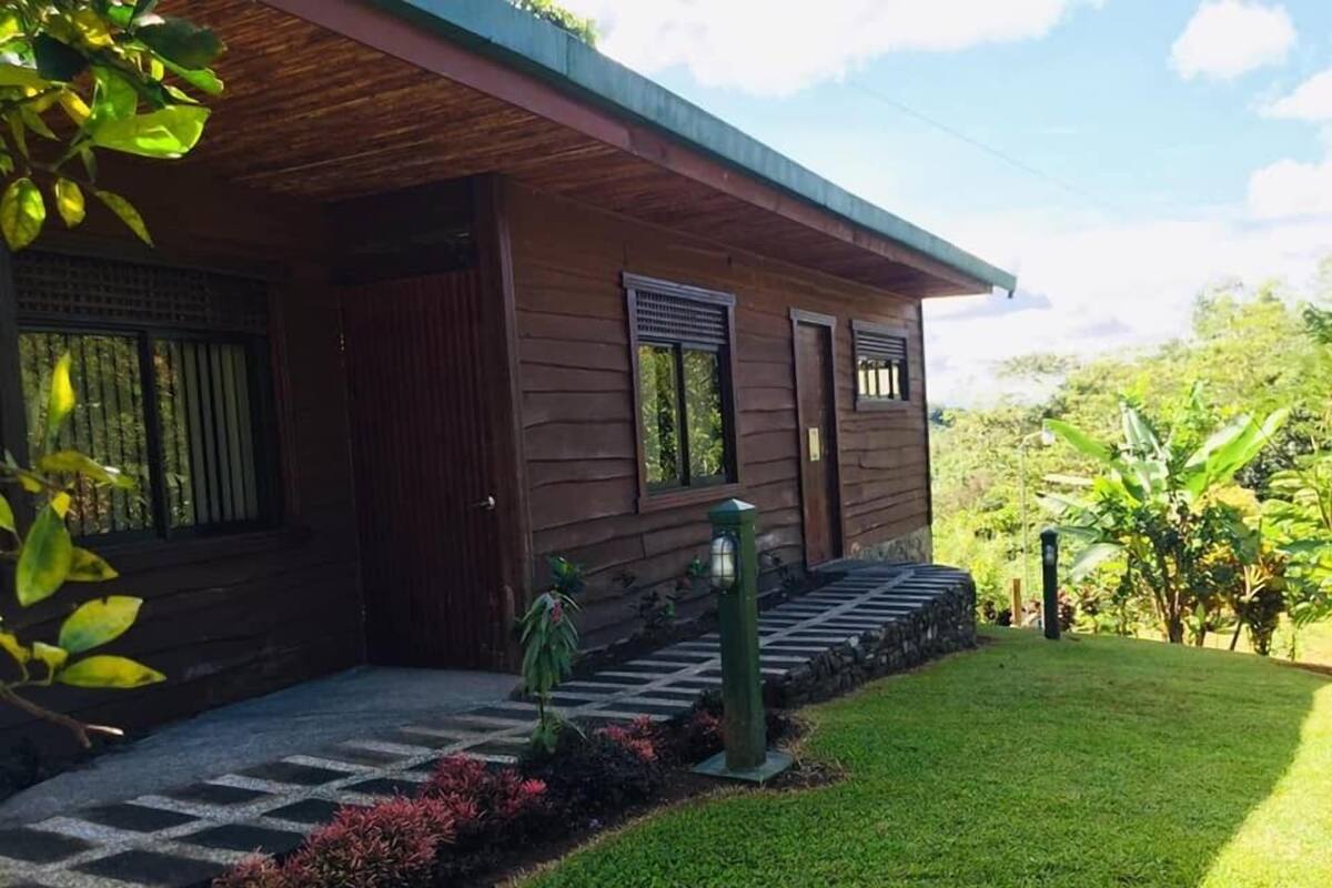 Une maison en bois avec un porche, un chemin de pierre et une pelouse bien entretenue.
