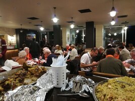 A crowded restaurant with multiple tables and people dining.