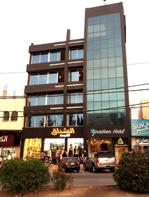 Un edificio moderno con varios pisos, con fachada de vidrio y entrada a nivel de calle.
