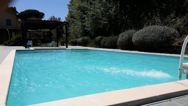 Una piscina rectangular con agua cristalina y un borde de baldosas.