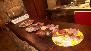 Una barra de madera con tres platos de carnes y quesos variados.