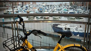 A yellow bicycle with a basket and a lock, parked on a balcony with a view of a marina filled with boats. - Hull Trinity Backpackers (Hull)