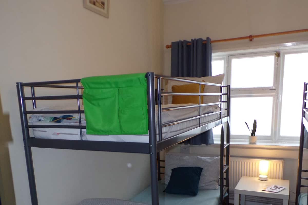 Une chambre avec un lit superposé, une petite table et une fenêtre.