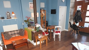 A furnished living room with a sofa, a table, a chair, and a small stool. - Hull Trinity Backpackers (Hull)