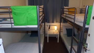 A bunk bed room with a small table and a lamp between the beds.
