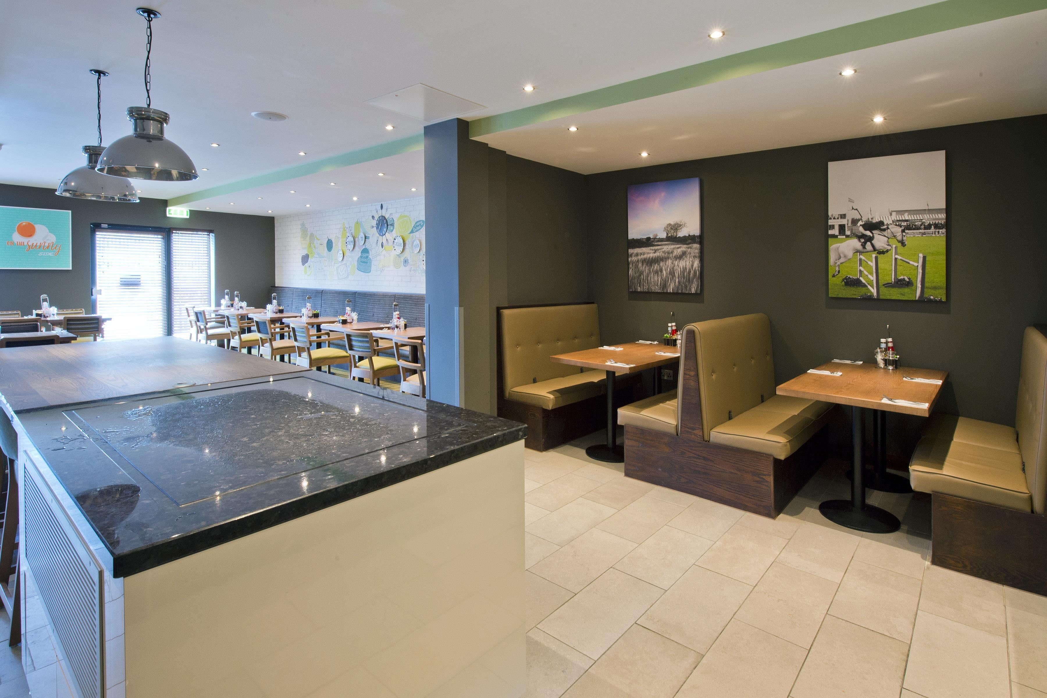 A restaurant with a central island, booths, and high chairs.