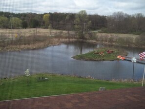 A view of a lake with a small island, a dock, and a flag. - BMI Bed & Breakfast and Oasis (Richland)