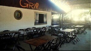 An outdoor dining area with tables and chairs, a clock on the wall, and a sign with the word "GRIN". - Hotel Bellavista (Bonito)