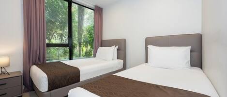 A hotel room with two beds, a nightstand, and a window with curtains.