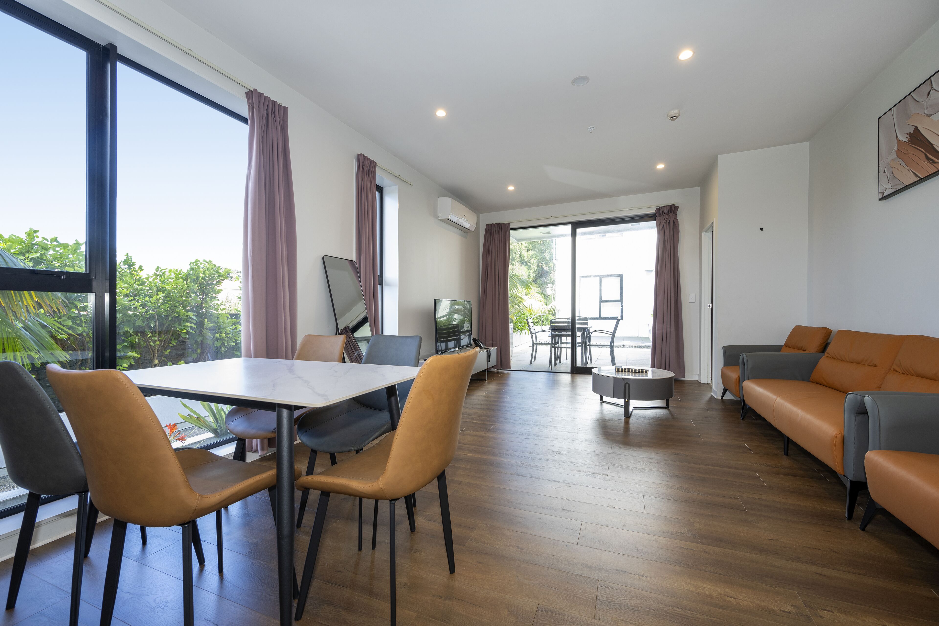 A spacious living area with a dining table, chairs, a sofa, and a TV.