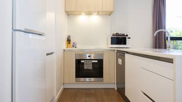 A compact kitchen with a built-in oven, microwave, and stainless steel refrigerator.