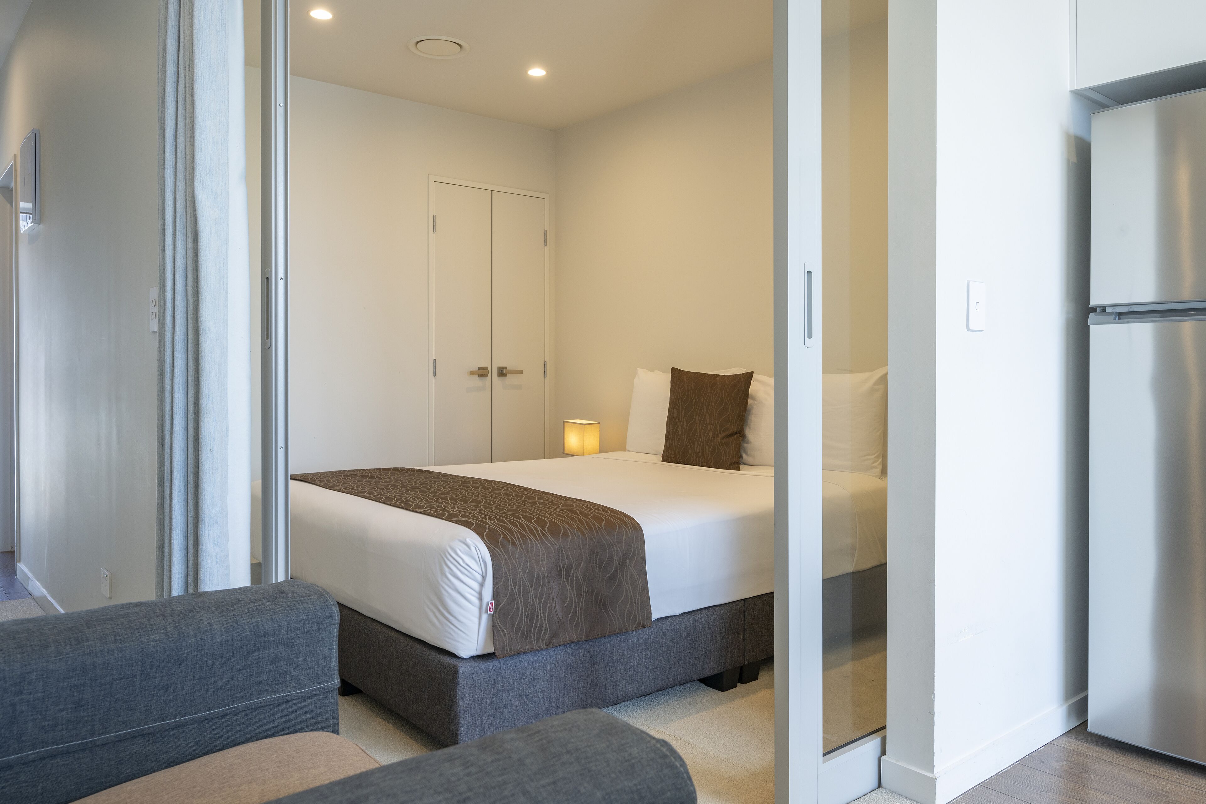 Een moderne hotelkamer met een bed, een slaapbank en een koelkast.