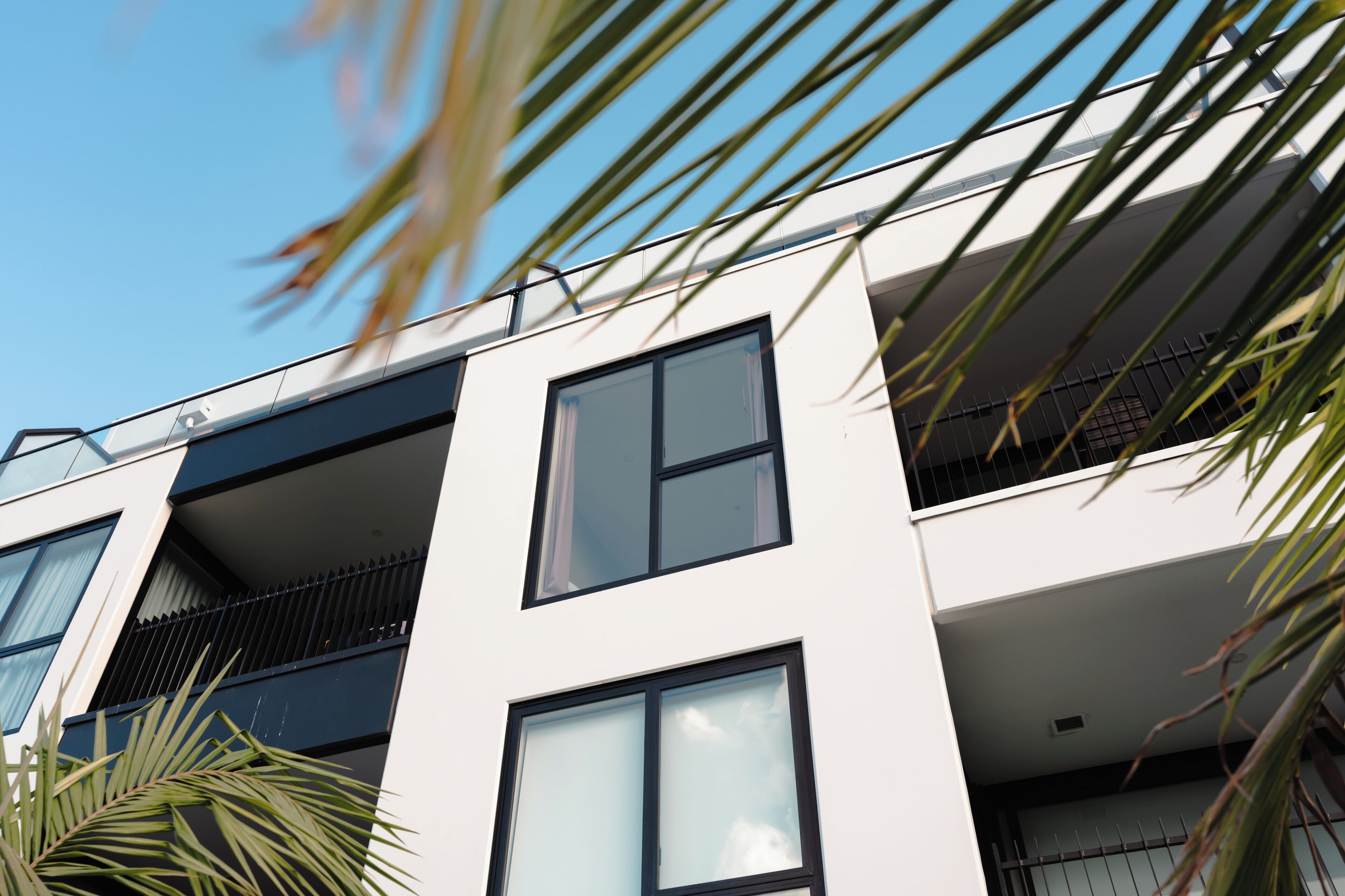 Un bâtiment moderne doté de nombreux balcons, de grandes fenêtres et surplombant un ciel dégagé.