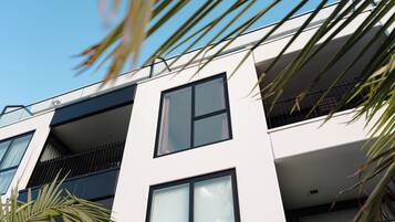 Un bâtiment moderne doté de nombreux balcons, de grandes fenêtres et surplombant un ciel dégagé.