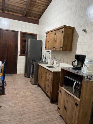 Une cuisine avec des meubles de rangement en bois, un réfrigérateur, une cuisinière et un four à micro-ondes.