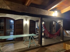Une pièce avec un plafond en bois, un luminaire, un hamac et une table.