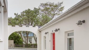 En smal, asfalterad gångväg som leder fram till en byggnad med en röd dörr och fönster.