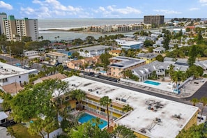 Une ville côtière où se côtoient des immeubles résidentiels et commerciaux, avec une piscine bien visible et une plage en arrière-plan.