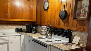 A kitchen with wooden cabinets, a stove, a coffee maker, and a kettle.