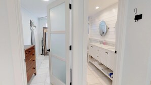 A modern bathroom with a white vanity, a mirror, and a towel rack.