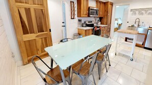 A modern kitchen with a glass dining table, wooden cabinets, and a sliding door.