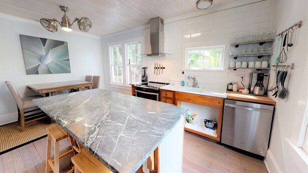 A modern kitchen with a marble countertop, wooden cabinetry, and stainless steel appliances.