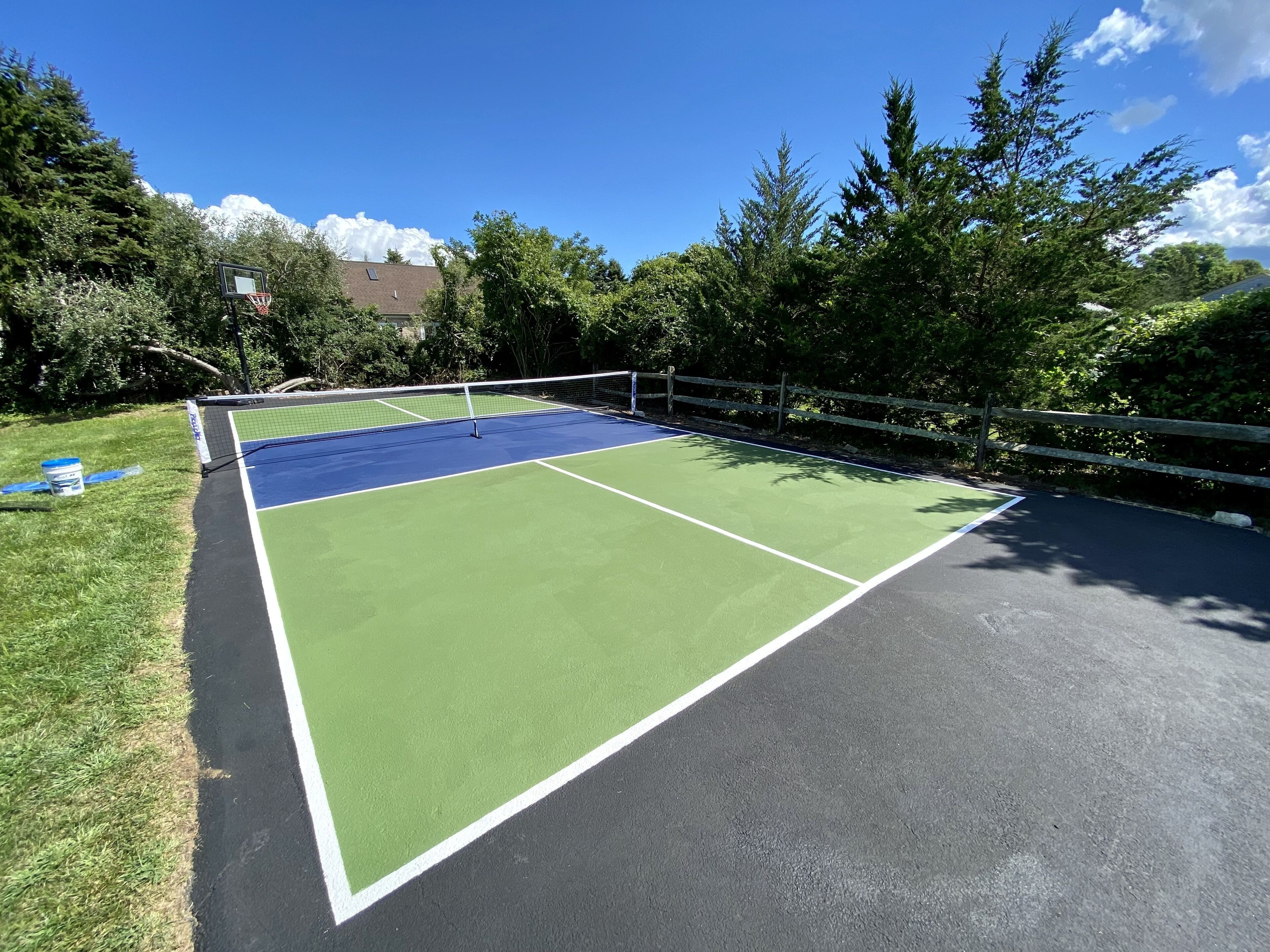 Pistes de tennis amb xarxa, envoltades per arbres i una tanca de fusta.