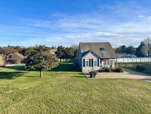 A house with a large lawn, a small porch, and a fenced yard. - This Romantic Cottage is Simply a Cut Above -  (Edgartown)