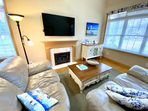 A living room with a fireplace, leather sofas, a coffee table, and a flat-screen TV. - This Romantic Cottage is Simply a Cut Above -  (Edgartown)