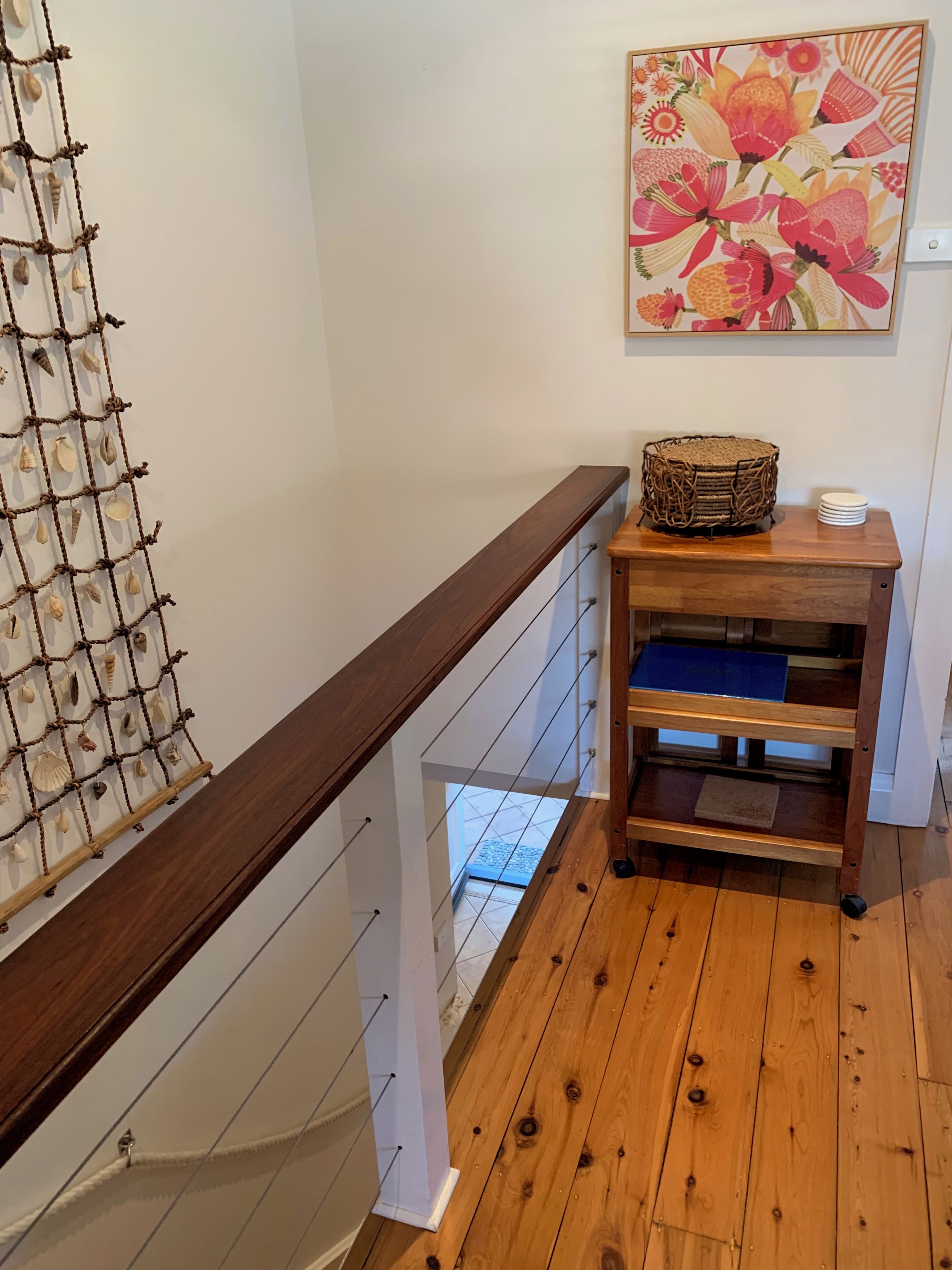 Una escalera de madera con decoración de red de cuerda y una consola de madera con una cesta y platos.