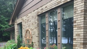 A brick house with large windows, a wooden arched window, and a garden with various plants and flowers. - Waterfront Home with Stunning Views .. Dog friendly , and great fishing !!! (Douglas)