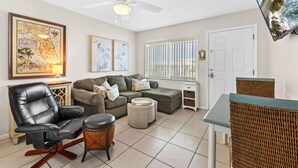 A living room with a sofa, a recliner, a coffee table, and a television mounted on the wall.