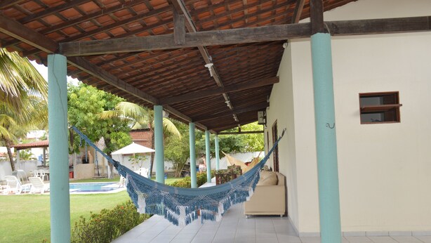 A covered outdoor area with a hammock, a pool, and a lawn. - Beach house with leisure area and deserted beach with natural pools. (sao miguel dos milagres)