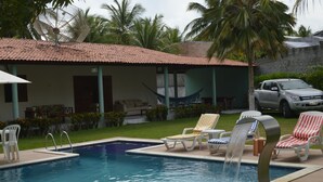 A swimming pool with lounge chairs, a hammock, and a truck parked nearby. - Beach house with leisure area and deserted beach with natural pools. (sao miguel dos milagres)