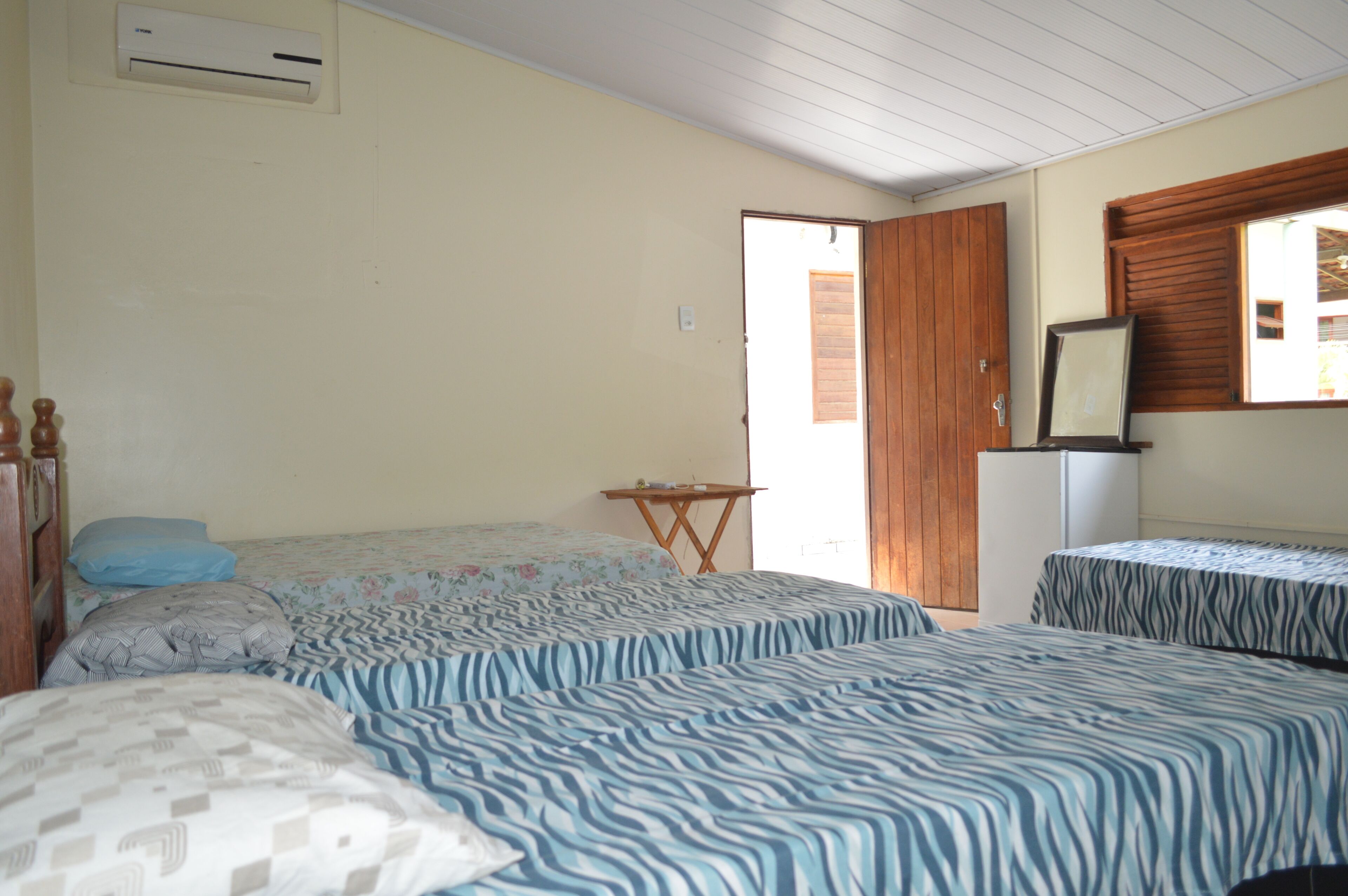 Quarto com duas camas, uma mesa pequena e um frigorífico.