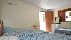 A bedroom with two beds, a small table, and a refrigerator. - Beach house with leisure area and deserted beach with natural pools. (sao miguel dos milagres)