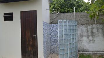 Um pequeno espaço ao ar livre cercado, com parede de azulejos, portão de metal e porta de madeira.