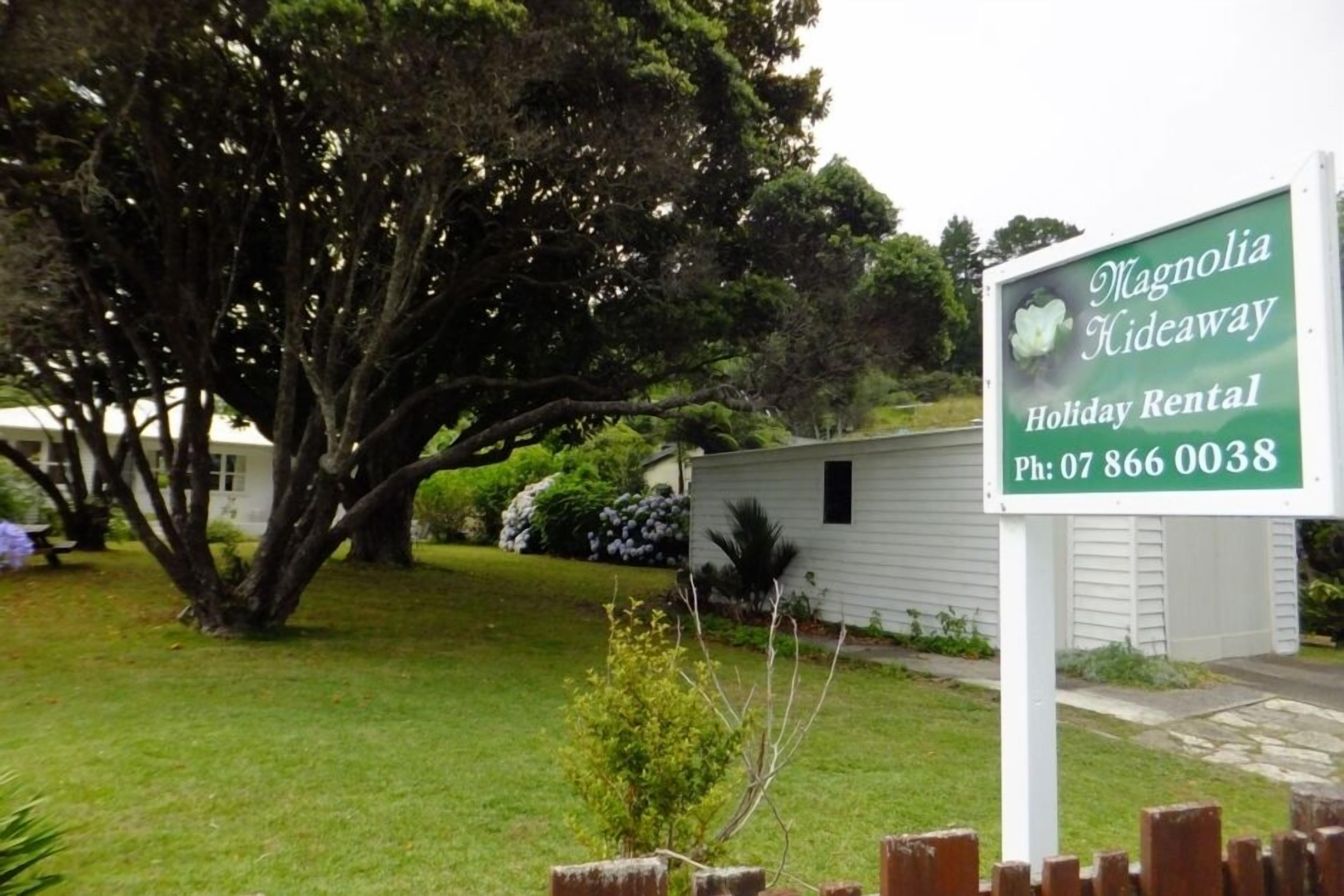 A sign for Magnolia Hideaway Holiday Rental with a contact phone number.