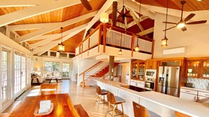 A spacious kitchen with a wooden island, a dining area with a long table, and a balcony with a wooden railing.
