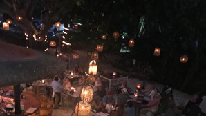An outdoor dining area with tables and chairs, surrounded by hanging lanterns. - The Condo is in the gated Sirenis Resort community. (Akumal)