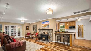 A spacious living room with a fireplace, a dining area, and a kitchen with a bar. - Go BeyOnd Ordinary & Escape to this Magnificent Wine Country Retreat, Golf, Hot Tub, Close to PDX (West Linn)