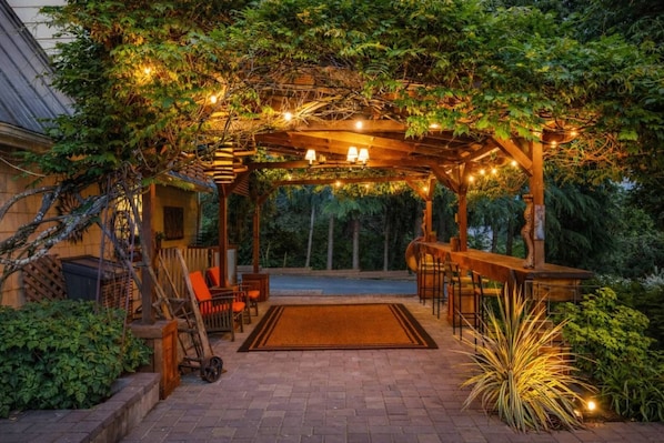 A covered patio area with a pergola, outdoor seating, and string lights.