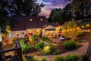 Una casa con un patio, una parrilla y luces colgantes.
