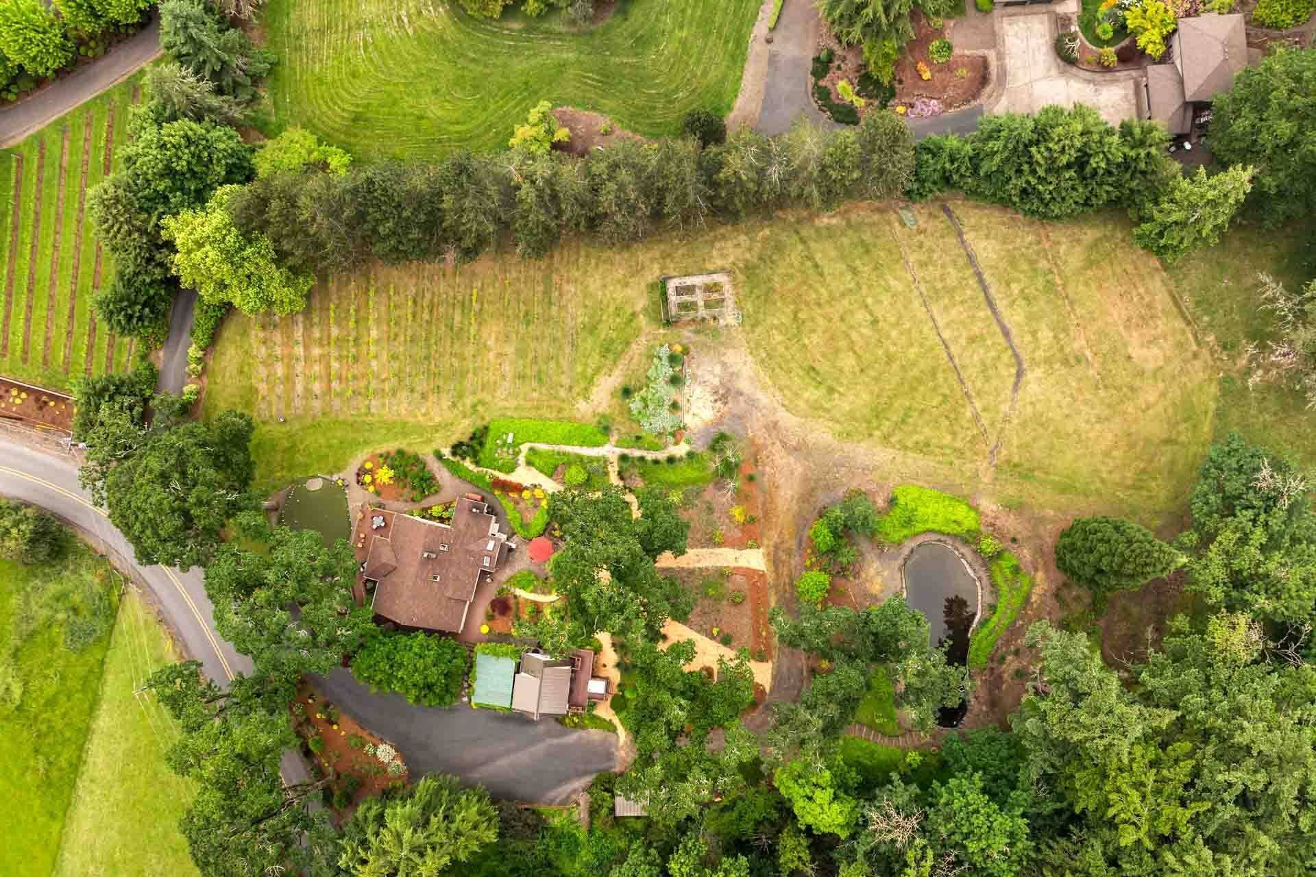 An aerial view of a residential area with a house, garden, and surrounding fields.